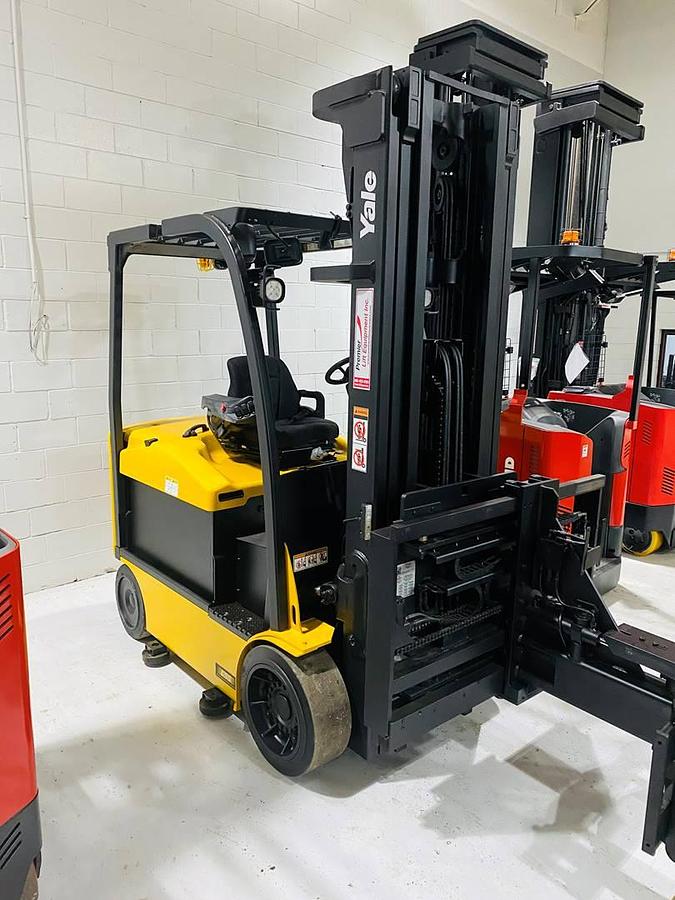 Opposite front side view of refurbished 2014 Yale ERC080VHN electric cushion tire forklift showing swing mast articulation, battery compartment, hydraulic lines, and CSA certification decal during U.S. deployment.