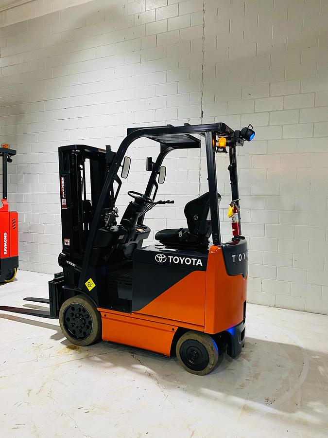 Rear angled side view of Toyota 8FBCU20 COM electric sit-down forklift showing counterweight, cab enclosure, and CSA-certified chassis – unit staged in Brampton ON
