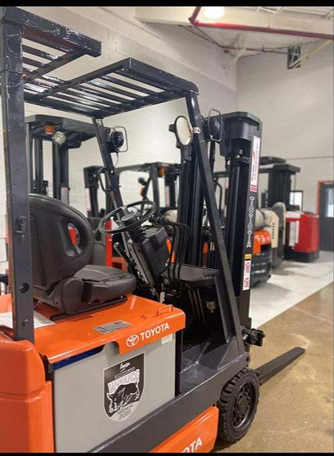 Rear angle side view of refurbished 1996 Toyota 5FBCU15 vintage electric 4-wheel sit-down forklift showing operator seat, counterweight, and rear tires during Ontario deployment