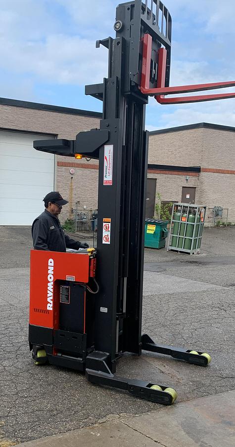 Technician inspecting and testing Budget Raymond ET‑R40TT reach truck during safety check.”