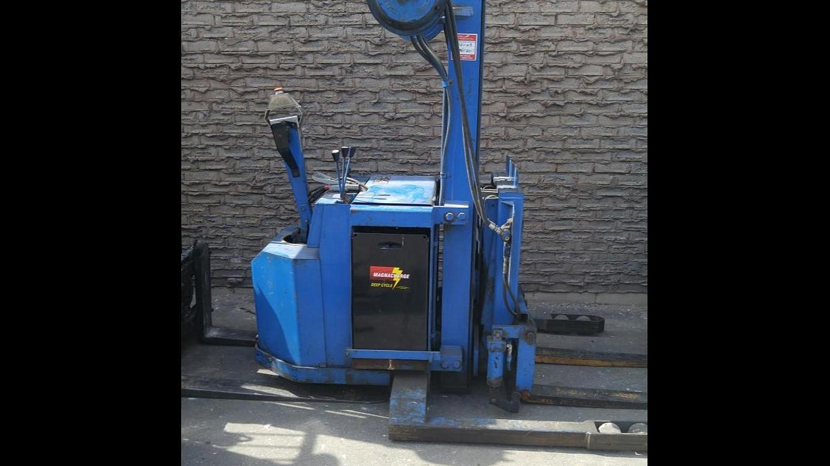 Side view of refurbished 1995 Blue Giant NA120W30 electric walkie straddle stacker reach showing straddle legs, two‑stage mast, 42" forks, and CSA certification decal during Brampton deployment.