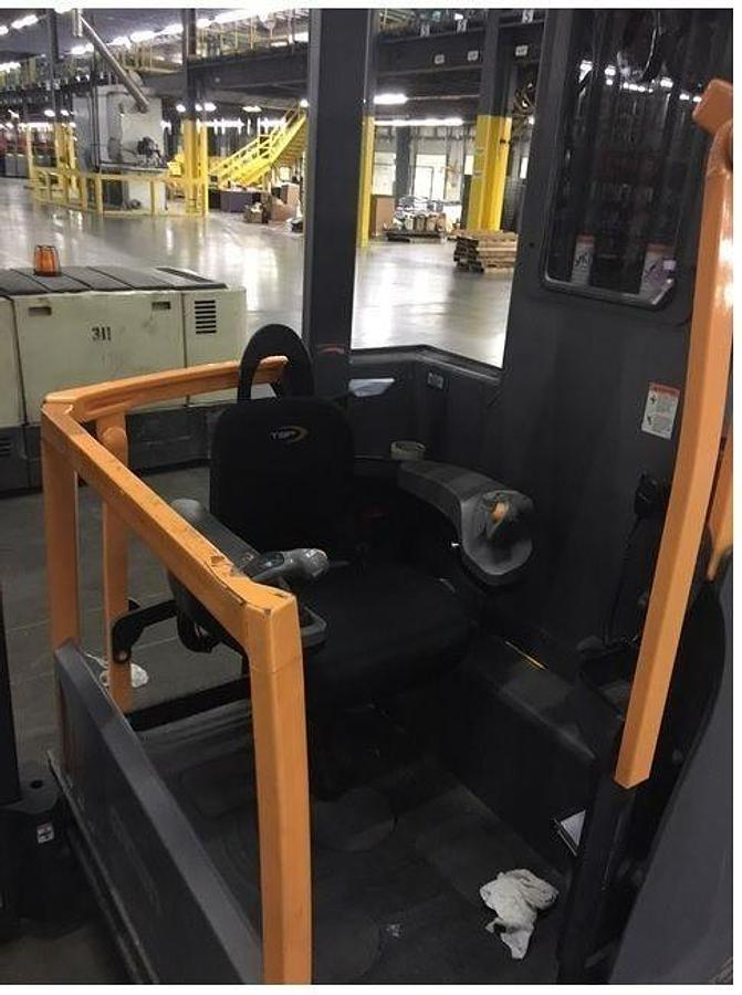 Operator compartment of refurbished 2017 Crown TSP7000 electric turret truck showing seat, steering wheel, hydraulic levers, wire guidance controls, and CSA certification decal during Ontario deployment.