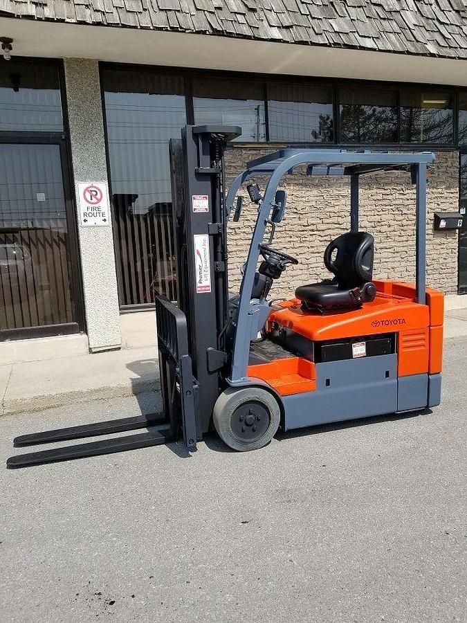 Profile view of 2014 Toyota 7FBEU15 electric forklift showing 3-wheel chassis, battery compartment, and mast configuration
