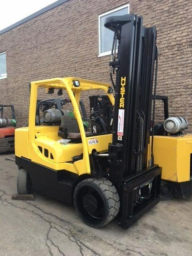 Head-on view of refurbished 2014 Hyster S155FT LPG cushion forklift showing high triple mast, 60" forks, monotrol pedal, and operator cab during Brampton deployment
