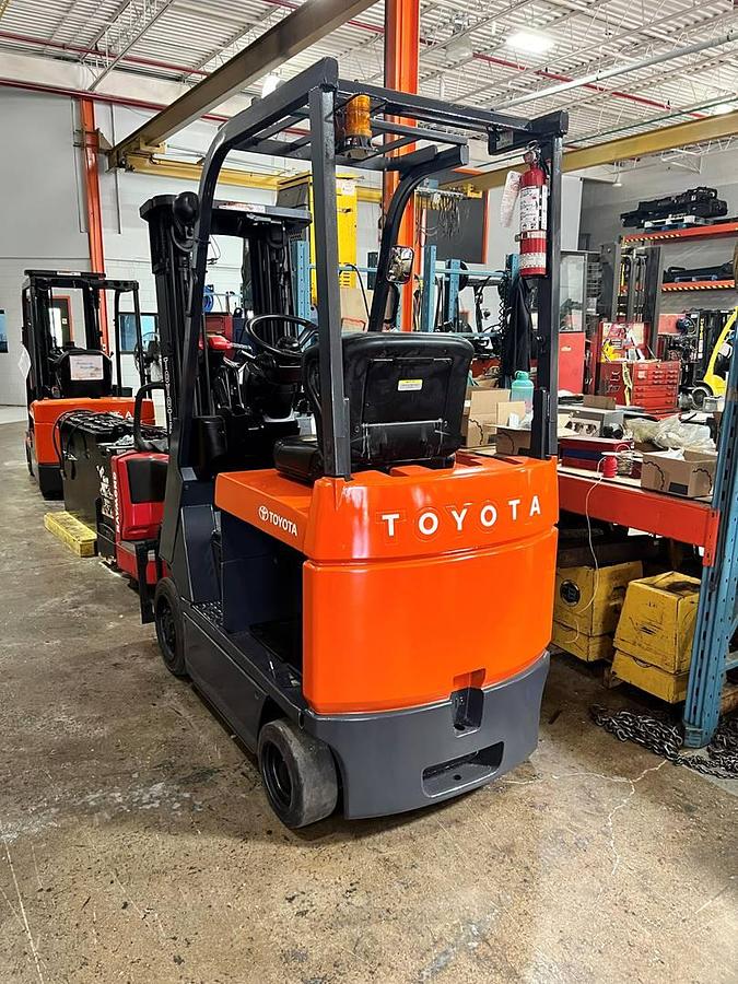 Rear angle side view of refurbished 2005 Toyota 7FBCU15 electric 4-wheel sit-down forklift showing operator seat, counterweight, and solid rear tires during Ontario deployment