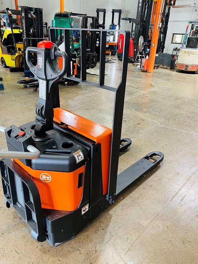 Front angled view of refurbished 2016 BT LPE200/8 electric walkie/rider pallet jack showing 27" x 45" forks, flip‑down operator platform, load backrest, battery compartment, and CSA certification decal during Ontario deployment.