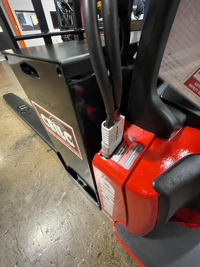 Top angle view of optional new 24V battery installed in 2015 Raymond 8410 electric rider pallet jack – CSA-certified chassis with onboard charger and clean battery compartment shown staged in Brampton ON – Premier Lift Equipment