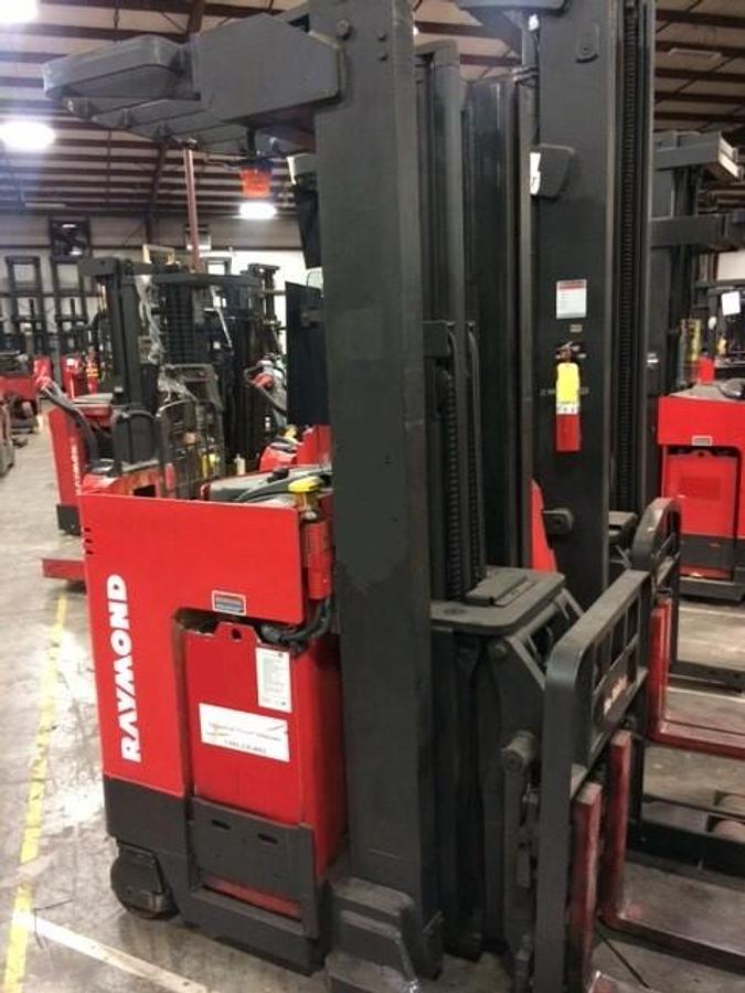 Front side angle of Raymond EASIDR30TT deep-reach forklift showing 216" triple mast, reach carriage, directional wheels, and narrow aisle chassis during Brampton deployment