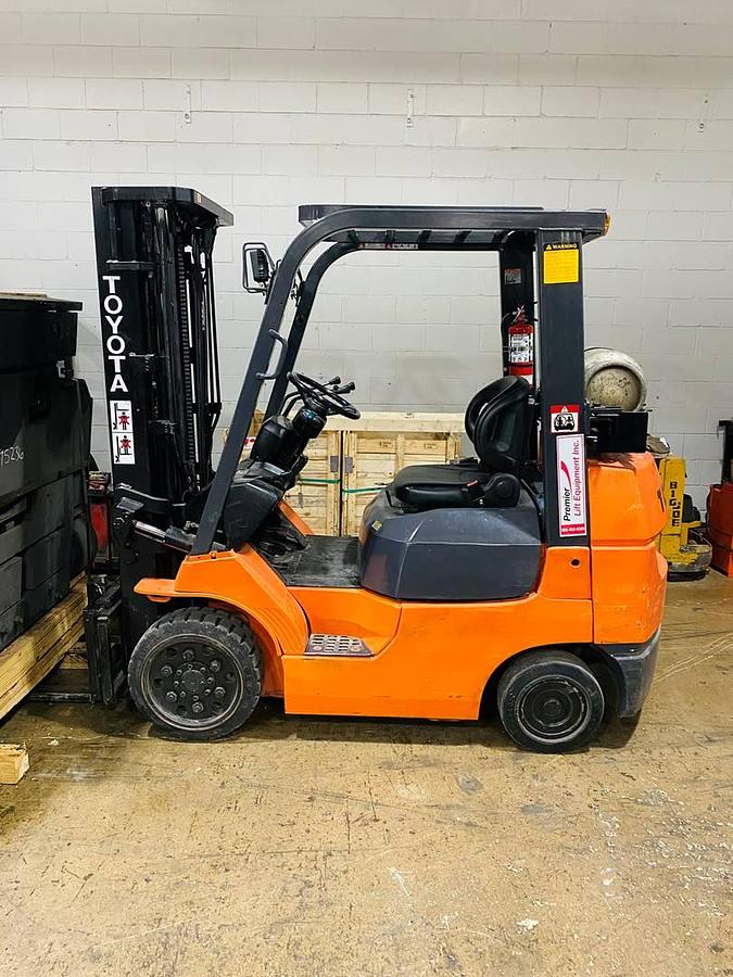 side view of vintage refurbished 2001 Toyota 7FGCU25 LP gas forklift showing operator cab, rear chassis, and CSA decal during Brampton deployment