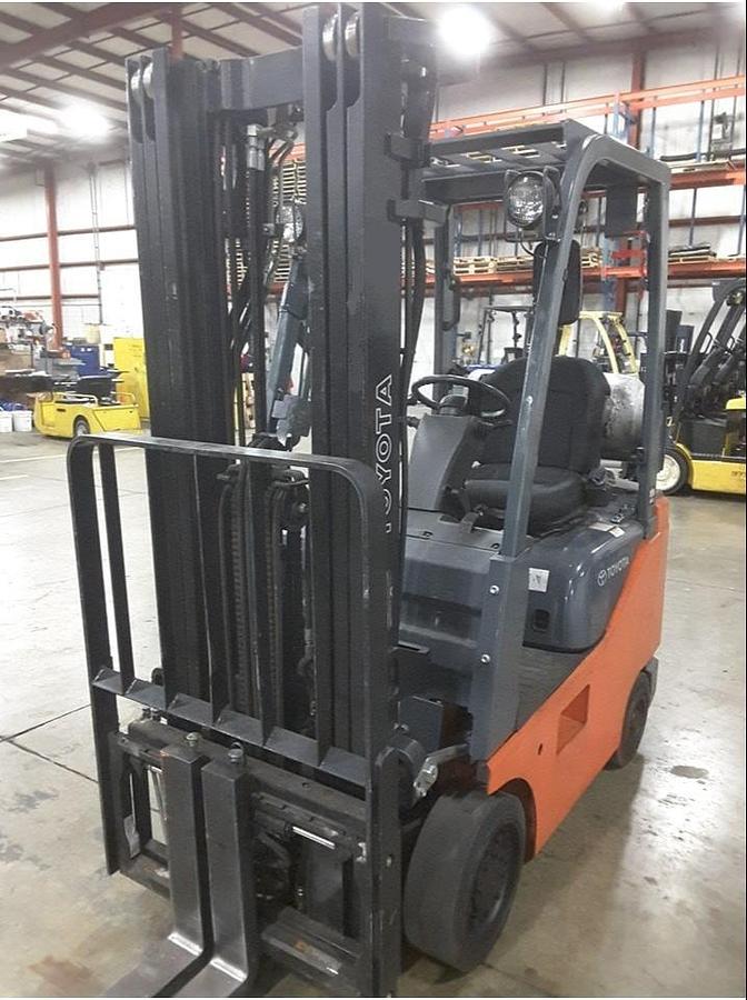 Front side view of refurbished 2014 Toyota 8FGCU18 LP gas forklift showing triple mast, 42" forks, and solid black cushion tires during Brampton deployment