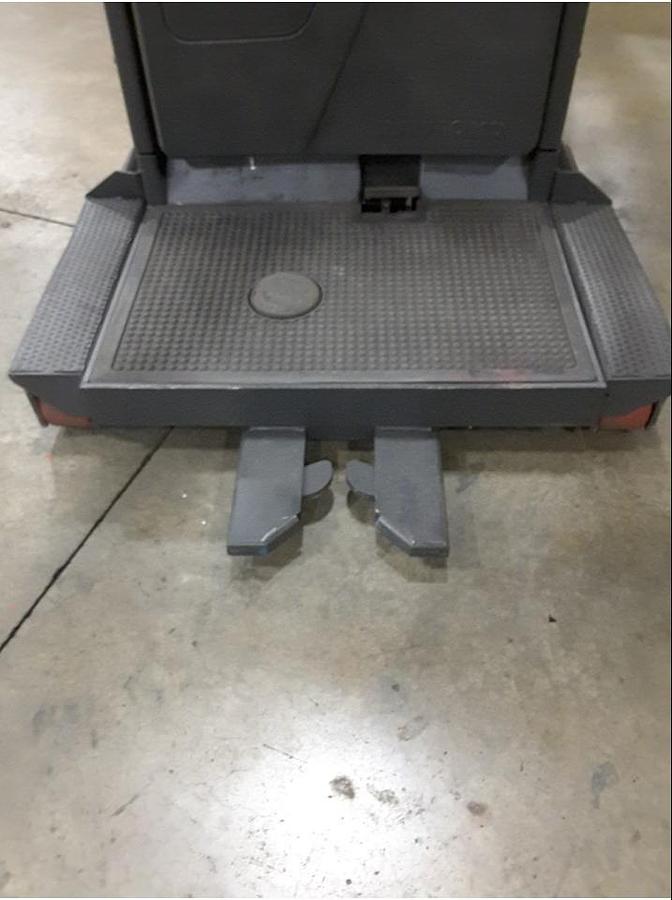 Close-up view of refurbished 2011 Raymond 560-OPC30TT electric order picker showing operator platform, pallet grabber arms, and CSA safety decals during Toronto deployment