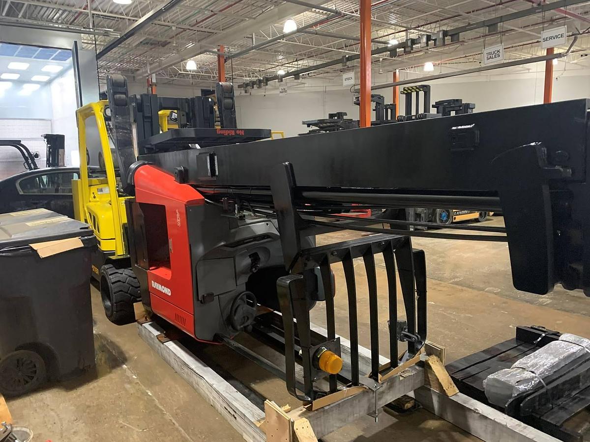 Opposite angled view of refurbished 2019 Raymond 772-R45TT electric reach truck laid down and cradled, showing reach carriage, mast rails, and operator cab during Toronto deployment