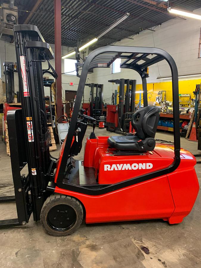 Side view of refurbished 2006 Raymond RTW35 electric 3-wheel sit-down forklift showing mast rails, CSA decal, and side shift carriage during Ontario deployment