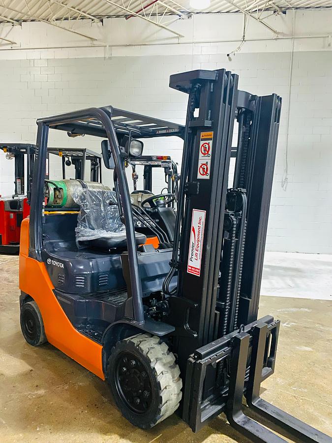 Front angle side view of 2019 Toyota 8FGCU20 propane forklift – CSA-certified 3,400 lb cushion tire chassis showing 198” triple mast, fork carriage, and propane tank bracket with safety decals applied, Brampton ON – Premier Lift Equipment