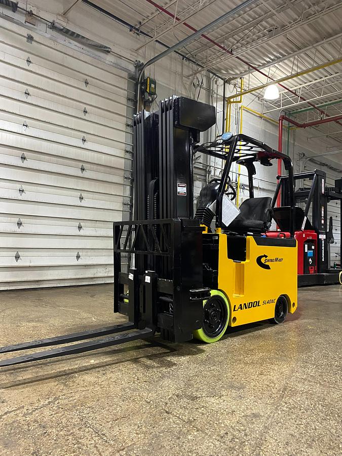 Side profile of refurbished 2017 Drexel SL-40AC electric SwingMast forklift showing 250" quad mast, pivoting carriage, directional wheels, and narrow aisle chassis during Brampton deployment
