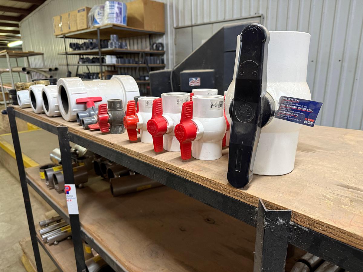 Used 5-SHELF RACK W/ CONTENTS OF PVC BALL VALVES & UNIONS, NETCO COLLAR LEAK REPAIR CLAMPS, (14+) BOXES 5/8” THRU 1” STUDS & NUTS