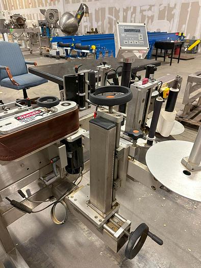 Used Quadrel E100 pressure sensitive wrap labeler for large bottles.