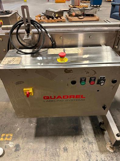 Used Quadrel E100 pressure sensitive wrap labeler for large bottles.